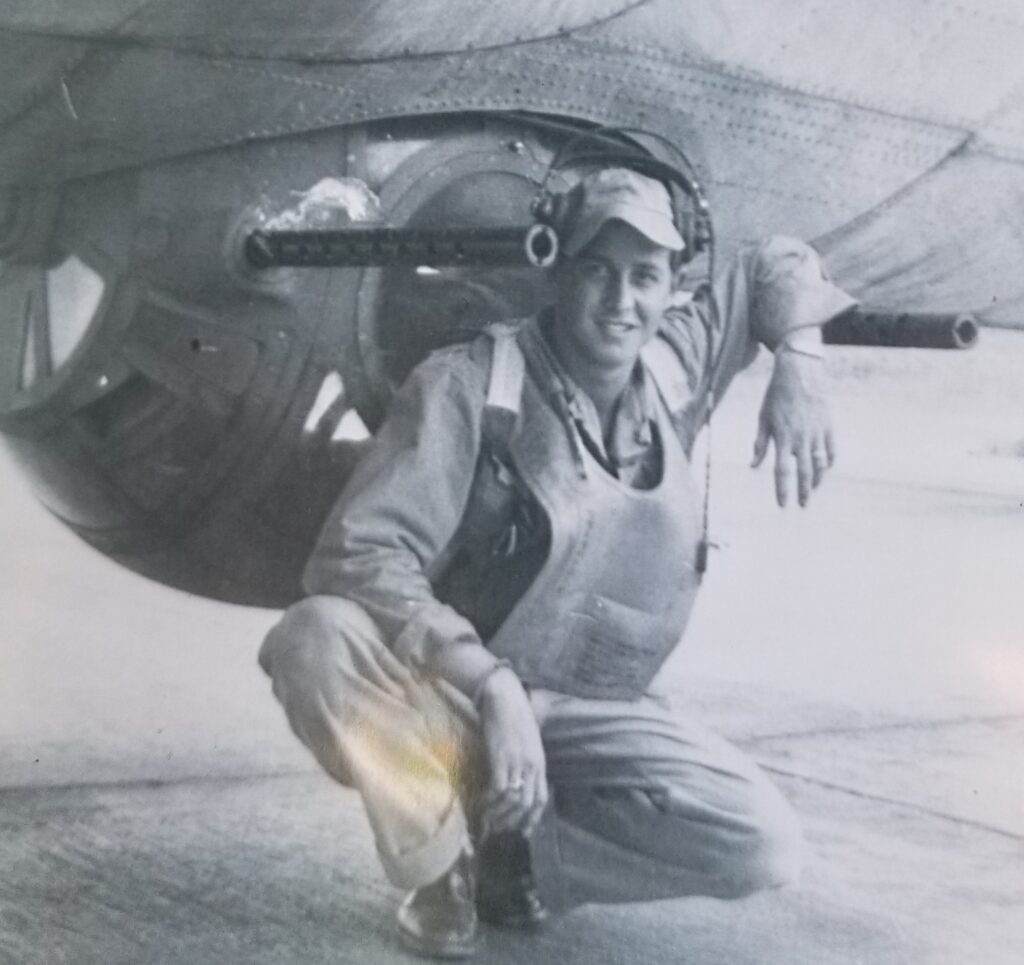 Bob Bright Bob bright as young airman sitting underneath his airplane next to the gun turret